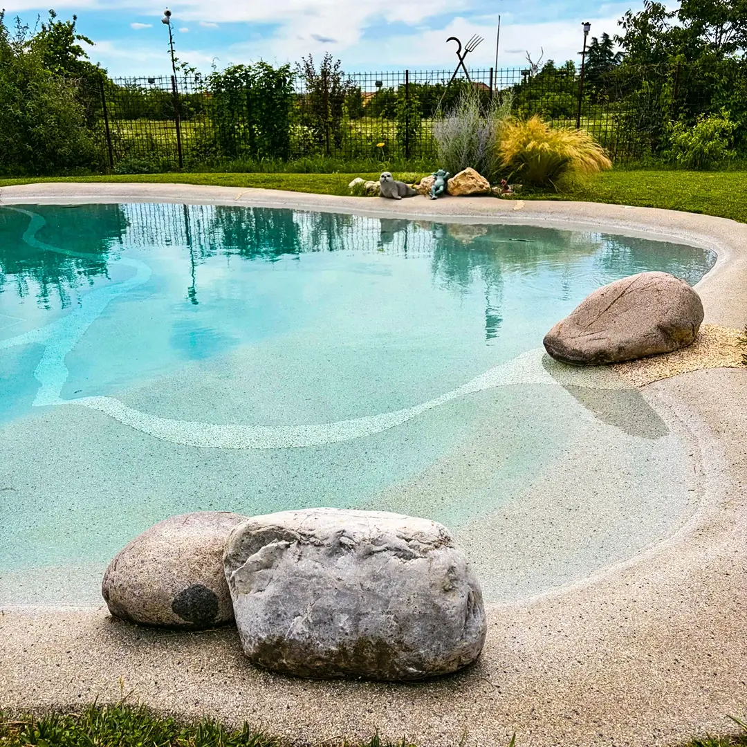 Natural boulders resting in the shallow beach entry of a sand pool