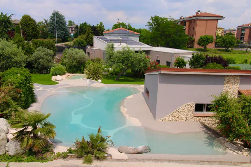 Free-form sand pool with palms and natural stone in a garden setting